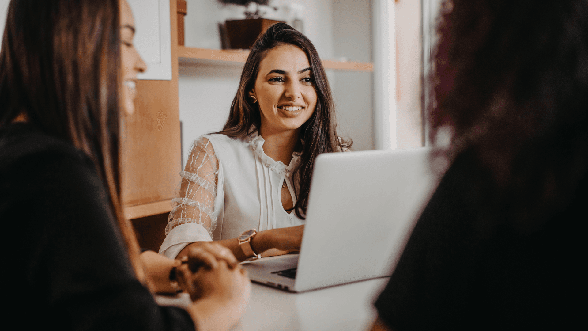 Profissional sorridente em reunião de equipe com notebook. Comunicação, liderança e colaboração no ambiente corporativo.